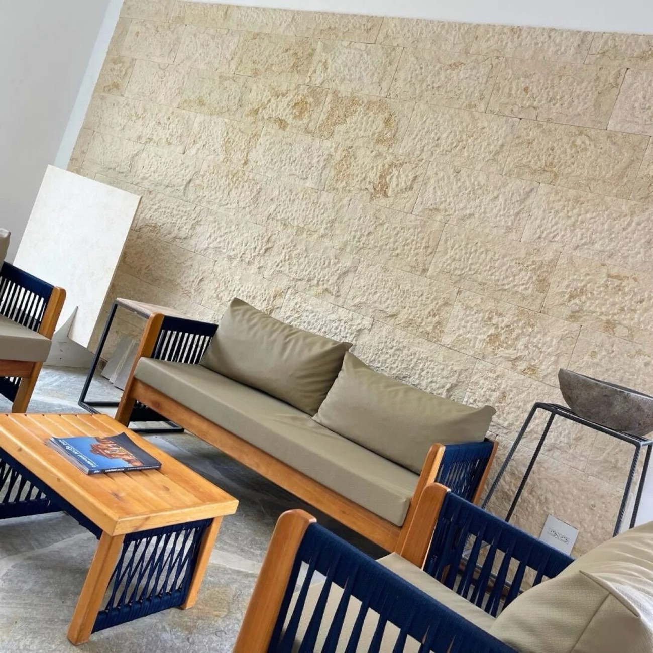 Parede de destaque revestida com pedra Rock Face em textura rústica clara atrás de sofá de varanda